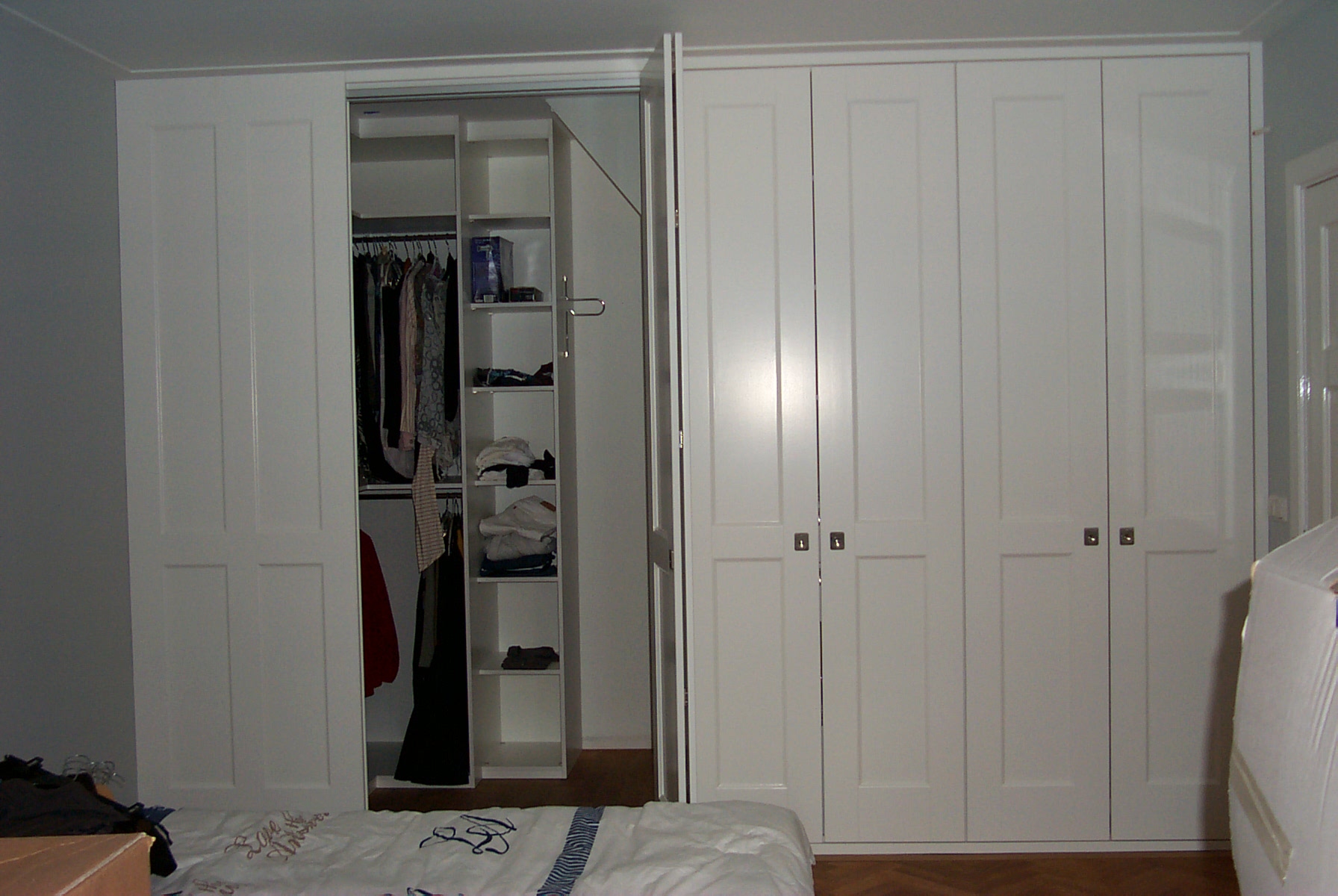 A wardrobe with a partial walk-in wardrobe, with storage shelves and hanging areas as well as a few drawers. The walk-in wardrobe is accessed by opening a folding door. Assembled by Flat Pack Happy.